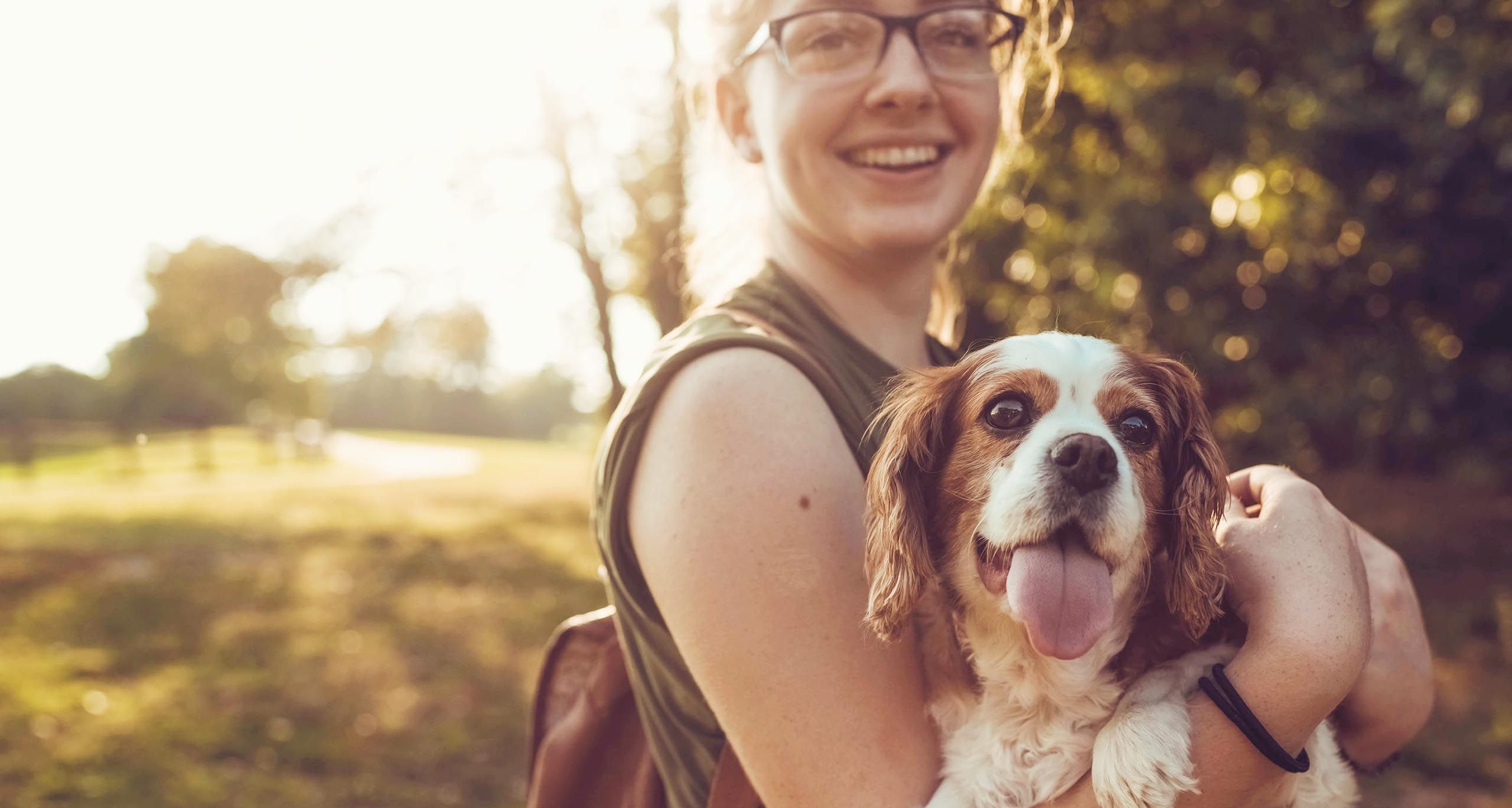glad kvinna håller i en hund ute i naturen